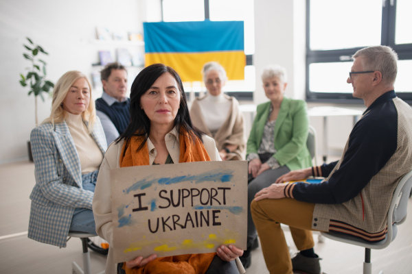 A group of seniors showing support when praying for Ukraine together in church community center.