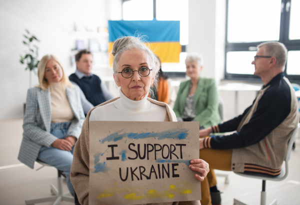 A group of seniors showing support when praying for Ukraine together in church community center.