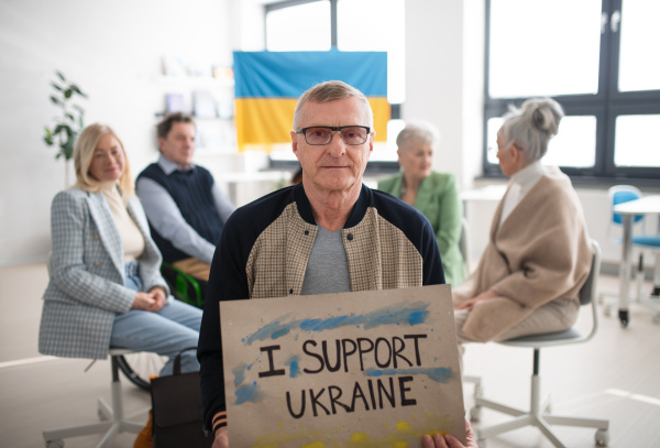 A group of seniors showing support when praying for Ukraine together in church community center.