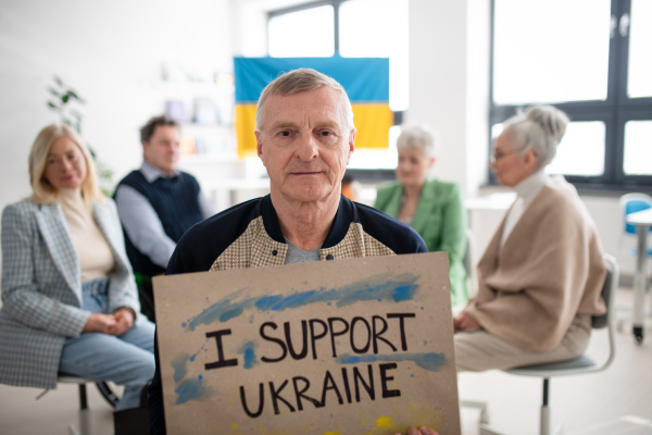 A group of seniors showing support when praying for Ukraine together in church community center.