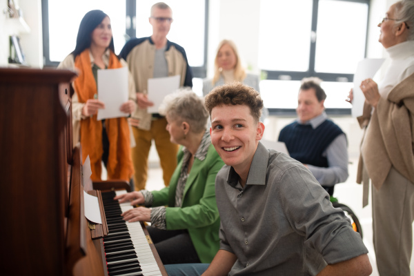 A group of seniors with young teacher singing together at choir rehearsal.