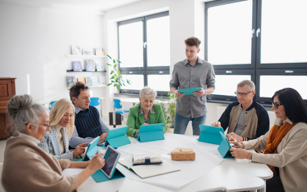 A group of seniors attending IT class in community centre with teacher