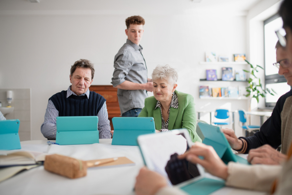 A group of seniors attending IT class in community centre with teacher