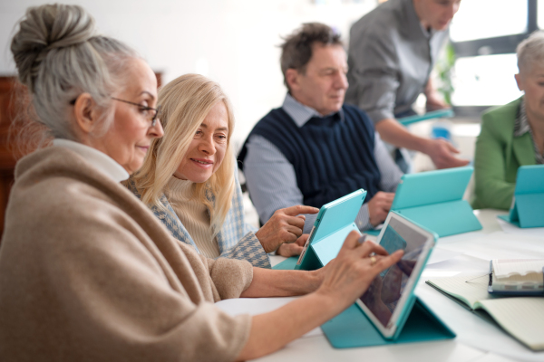 A group of seniors attending IT class in community centre with teacher