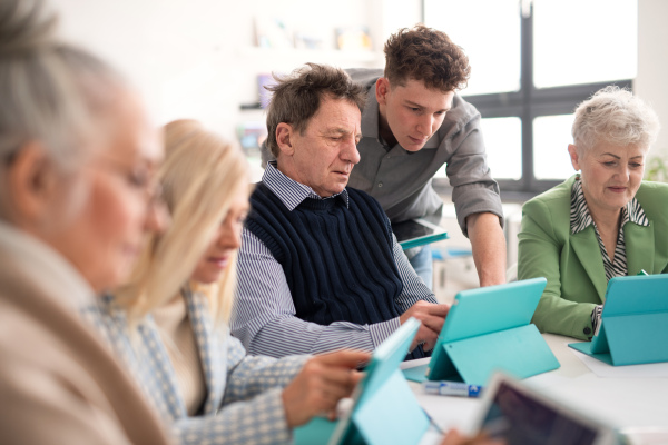 A group of seniors attending IT class in community centre with teacher