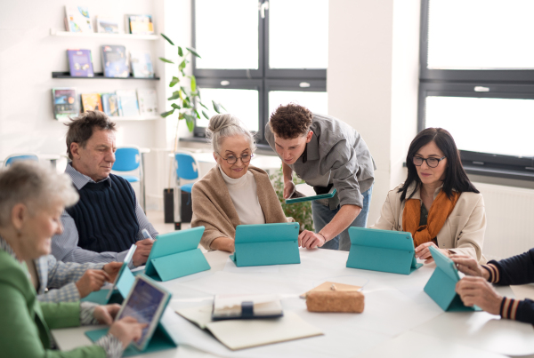 A group of seniors attending IT class in community centre with teacher