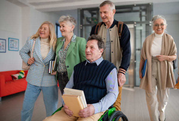 A group of happy senior students walking in corridor in university together.