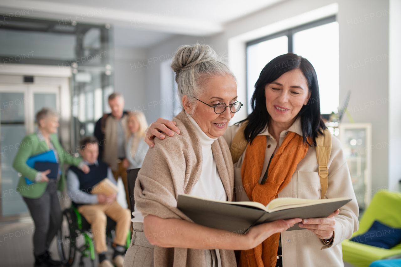 A happy mature woman student with book discussing with teacher in corridor in university.