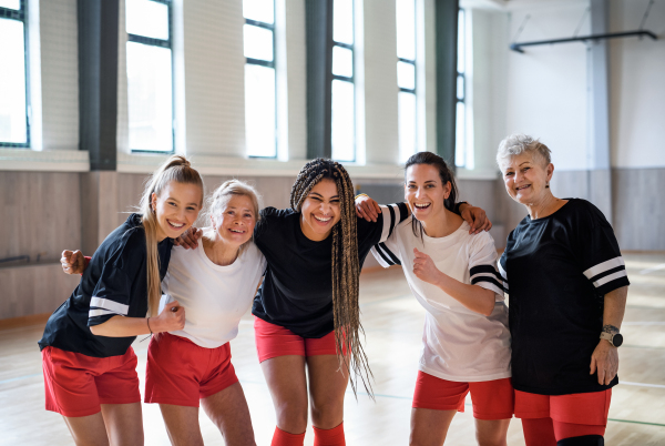 A group of young and old women together in gym looking at camera, sport team players.