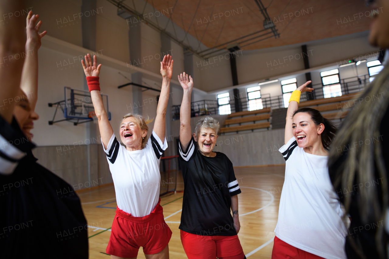 A group of young and old women, sports team players, in gym celebrating victory.