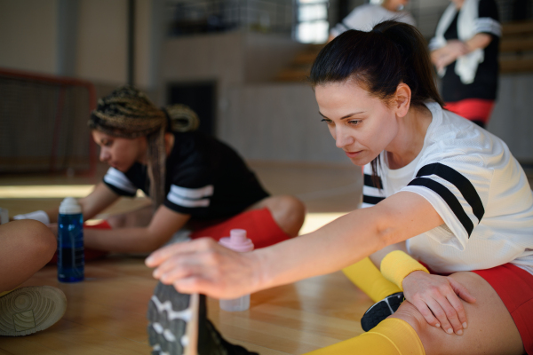 Happy women stretching before basketball match in a gym.