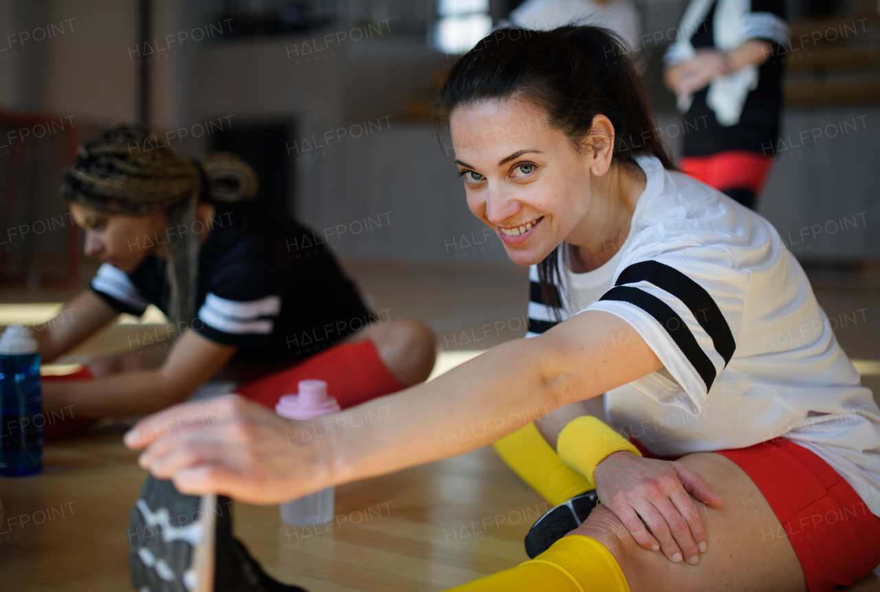 Happy women stretching before basketball match in a gym.