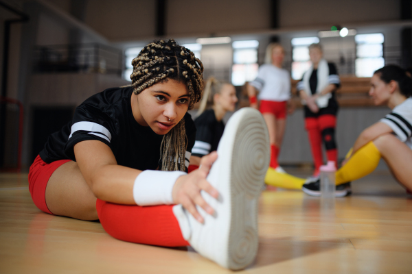 Group of multigenerational women, sports team players in gym stretching, warming up before match.