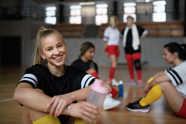 A group of young and old women, sports team players in gym sitting and resting after match.