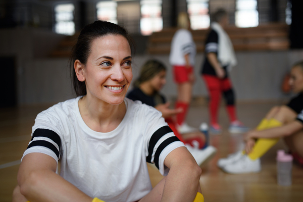 A group of young and old women, sports team players in gym sitting and resting after match.