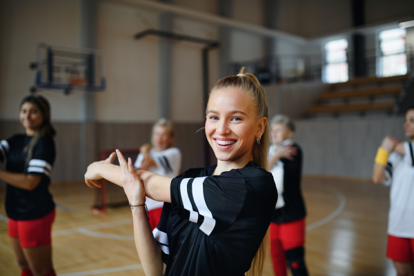 Group of multigenerational women, sports team players in gym stretching, warming up before match.