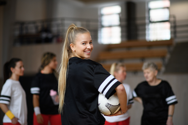 Rear view of young woman football player in gym during match.