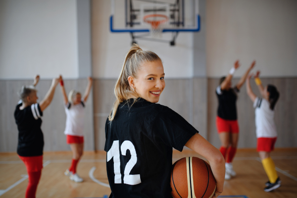 Rear view of young woman basketball player in gym during match.