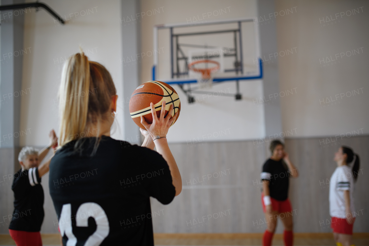 Rear view of young woman basketball player in gym during match.