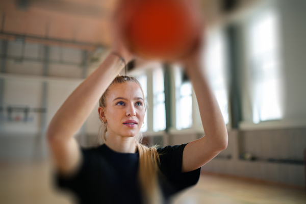 Rear view of young woman basketball player in gym during match.