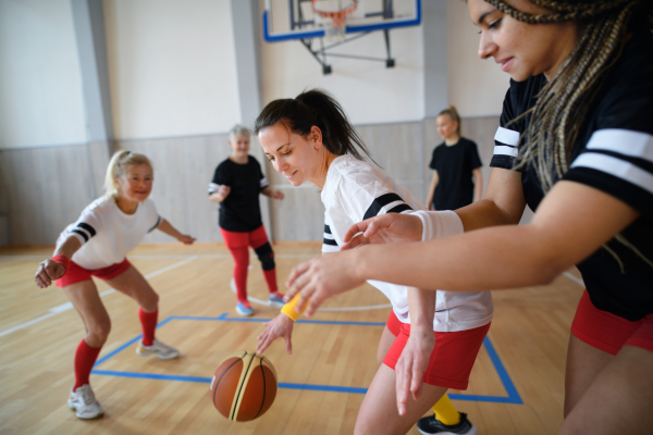 Multigenerational women playing a basketball match in gym.