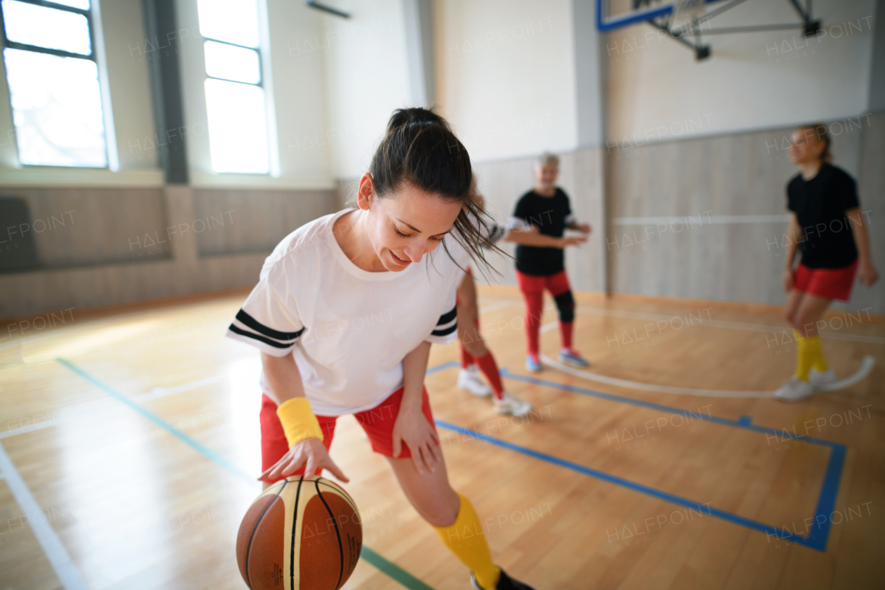 Multigenerational women playing a basketball match in gym.