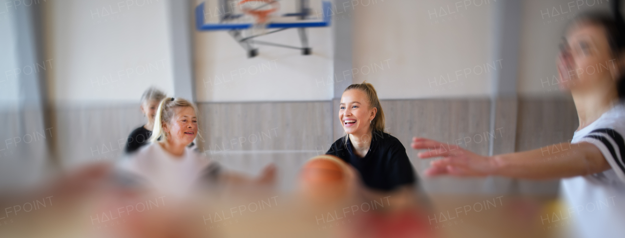 Multigenerational women playing a basketball match in gym.