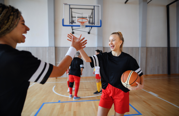 Young women, sports team players, in gym celebrating victory.