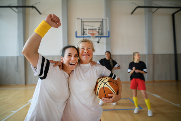 A group of young and old women, sports team players, in gym celebrating victory.