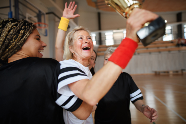 A group of young and old cheerful women, floorball team players, in gym cebrating victory.