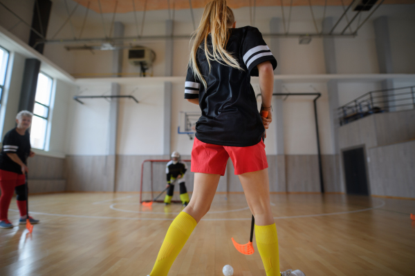 Rear view of woman, floorball player during match in a gym.