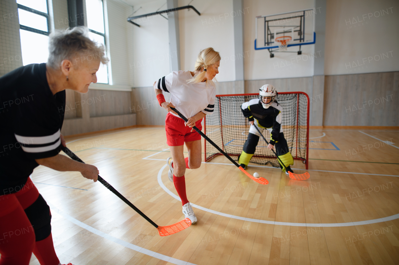 Multigenerational woman floorball team playing together in gym.