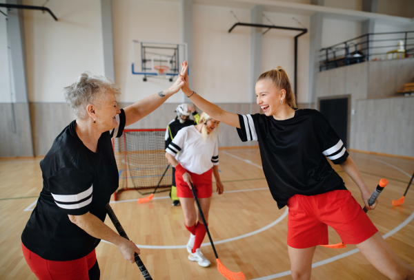 A group of young and old cheerful women, floorball team players, in gym cebrating victory.