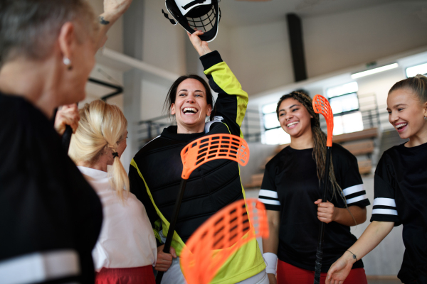 A group of young and old cheerful women, floorball team players, in gym cebrating victory.