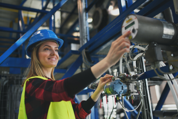 A woman worker woring in industrial factory, programming machine.