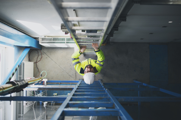 A top view of engineer in industrial factory climbing up the ladder.