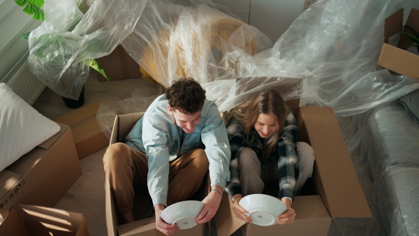 A cheerful young couple in their new apartment, having fun when unpacking. Conception of moving.