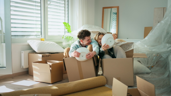 A cheerful young couple in their new apartment, having fun when unpacking. Conception of moving.