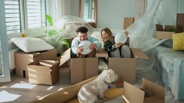 A cheerful young couple in their new apartment, having fun when unpacking. Conception of moving.