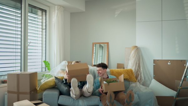 A cheerful young couple in their new apartment, carrying boxes. Conception of moving.