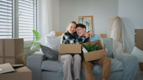 A cheerful young couple in their new apartment, carrying boxes. Conception of moving.