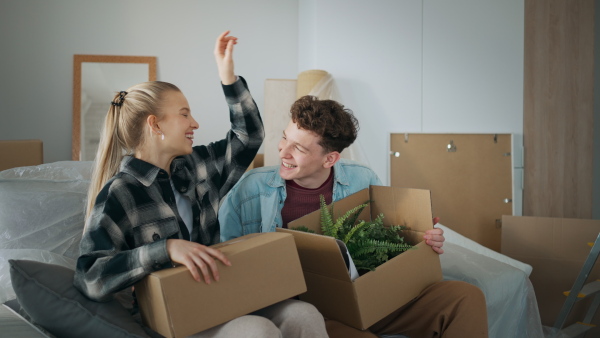 A cheerful young couple in their new apartment, carrying boxes. Conception of moving.