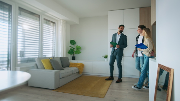 A happy young couple buying their new home and meeting real estate agent in apartment.