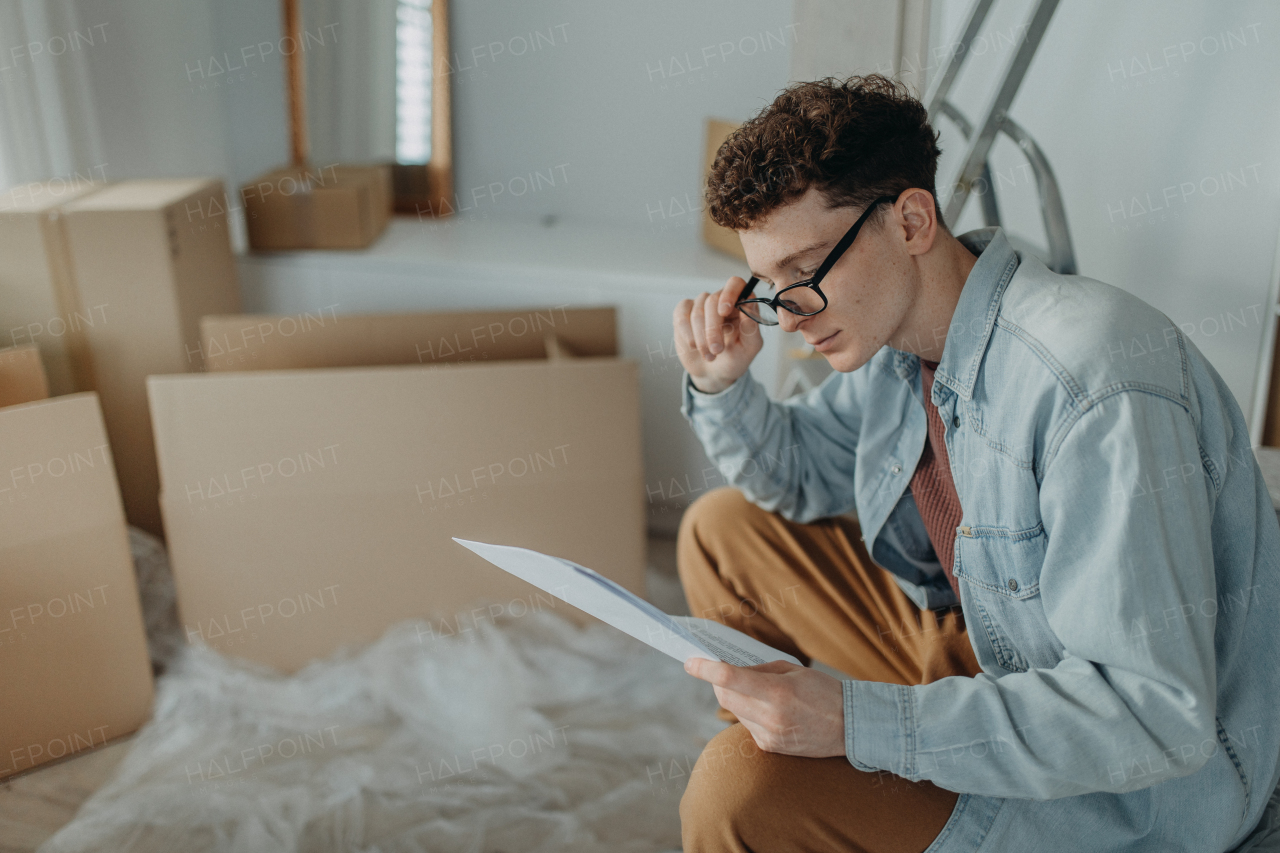 A young man in his new apartment reading contract. Conception of moving.