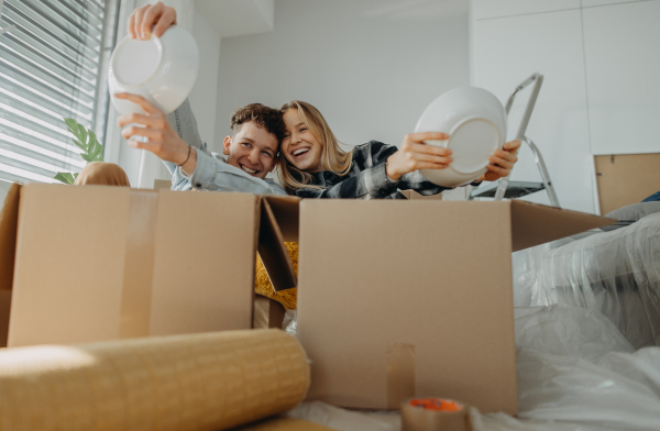 A cheerful young couple in their new apartment, having fun when unpacking. Conception of moving.