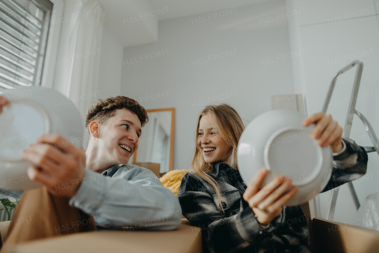 A cheerful young couple in their new apartment, having fun when unpacking. Conception of moving.