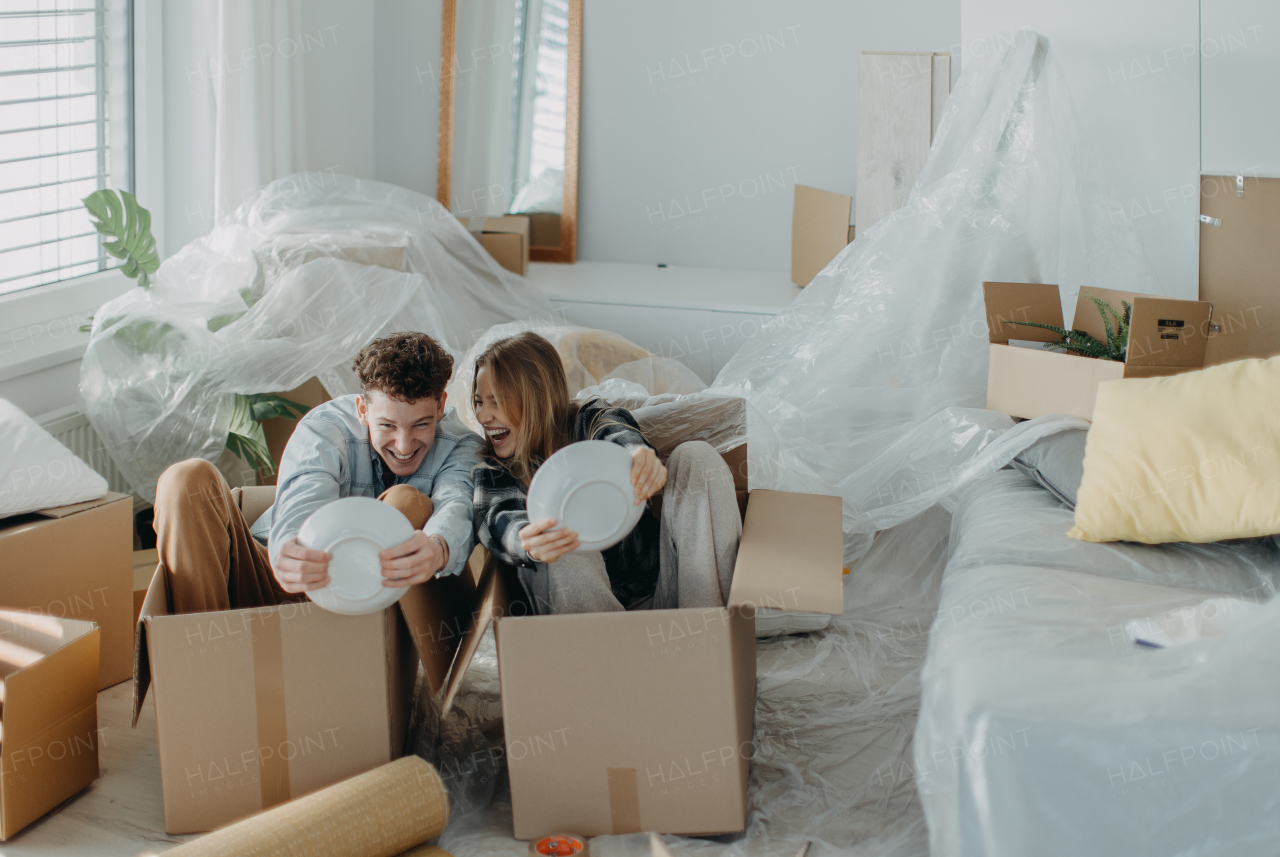 A cheerful young couple in their new apartment, having fun when unpacking. Conception of moving.