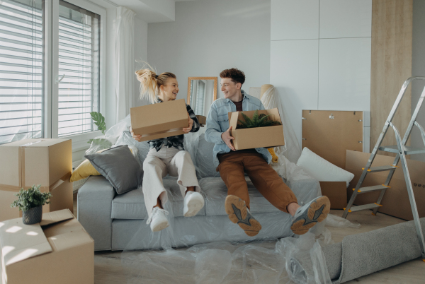 A cheerful young couple in their new apartment, carrying boxes. Conception of moving.