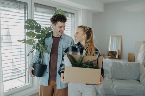 A cheerful young couple in their new apartment, carrying boxes. Conception of moving.