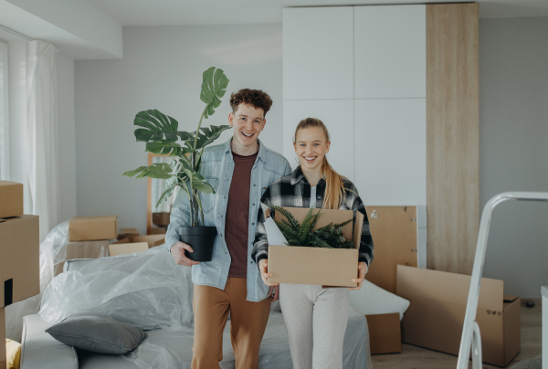 A cheerful young couple in their new apartment, carrying boxes. Conception of moving.